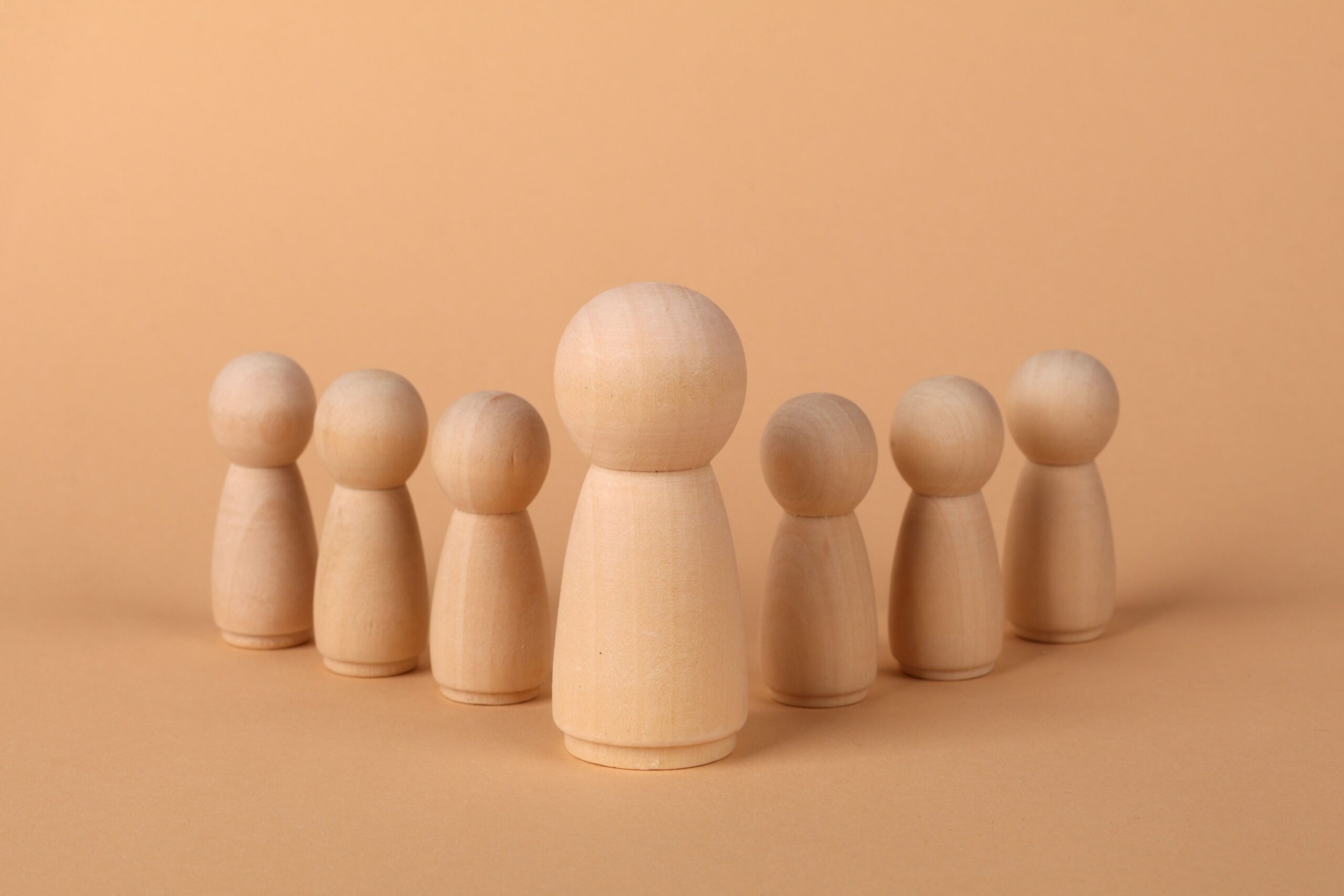 Set of minimalist wooden figures arranged in soft natural light on a beige background.